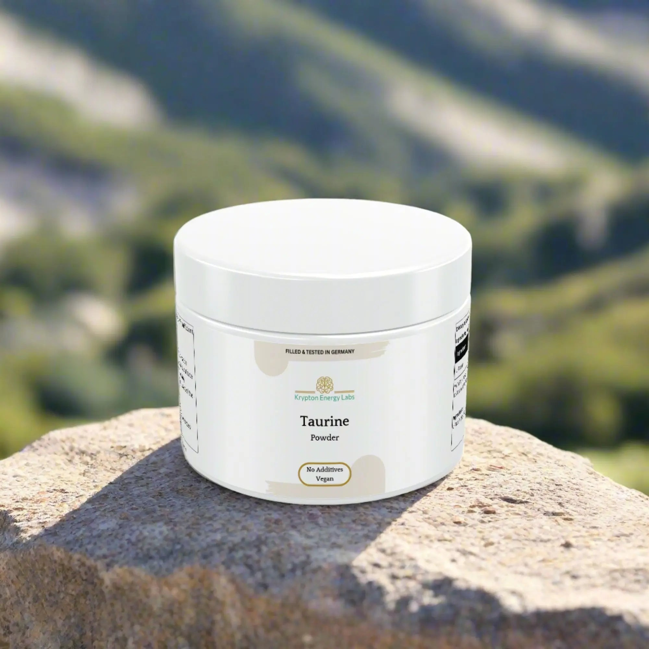 A white container of Taurine Powder from Krypton Energy Labs, labeled "VEGAN OK" and "No Additives," sits on a rock outdoors. Blurred green foliage and hills can be seen in the background, emphasizing a natural setting ideal for promoting cardiovascular health.